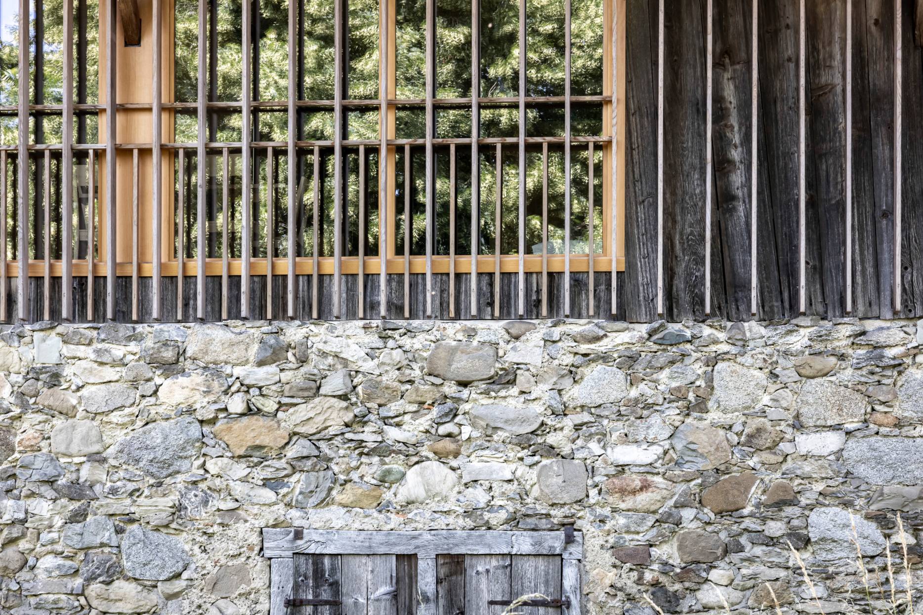 Detail Fassade Nord des Ökonomietrakts mit gemauertem Erdgeschoss und neuer Lamellenkonstruktion vor der Fassade. Foto: Elia Schneider, 2024