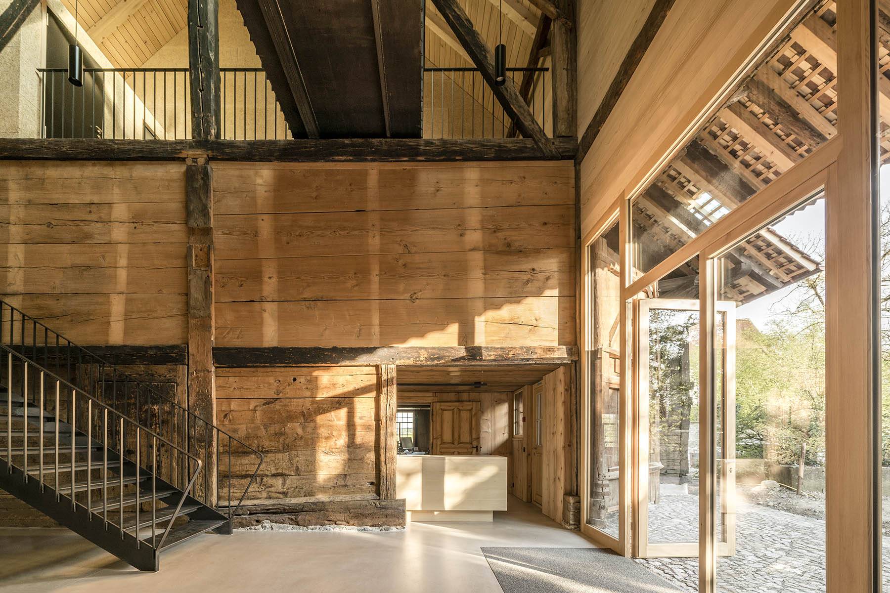 Entrée im ehemaligen Tenn mit Blick auf die historische Bohlenständerwand mit Firstständer. Foto: Gian Salis Architektur, 2021