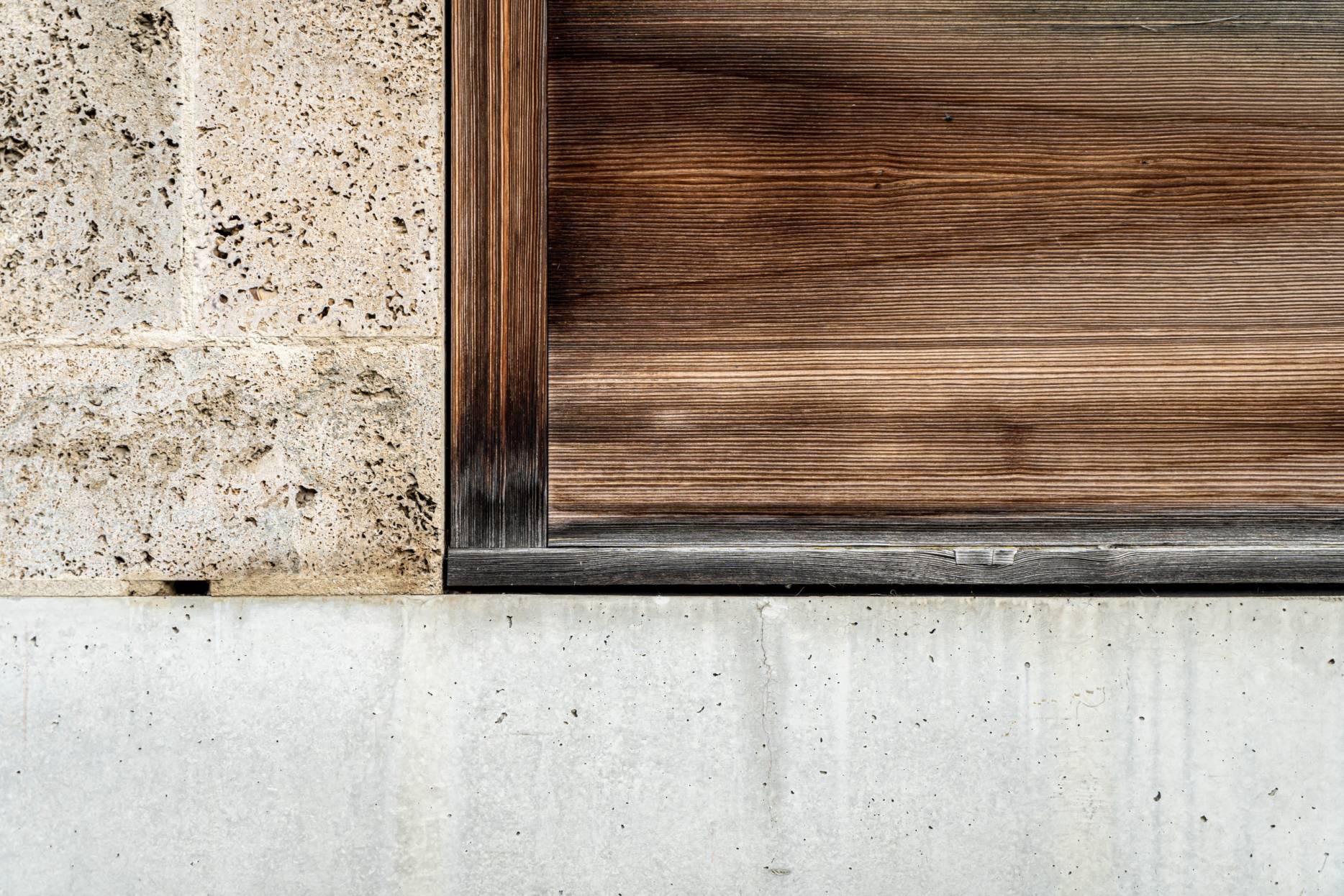 Detail Fassade mit drei Materialien: Travertin, Beton und Lärchenholz. Foto: Elia Schneider, 2022