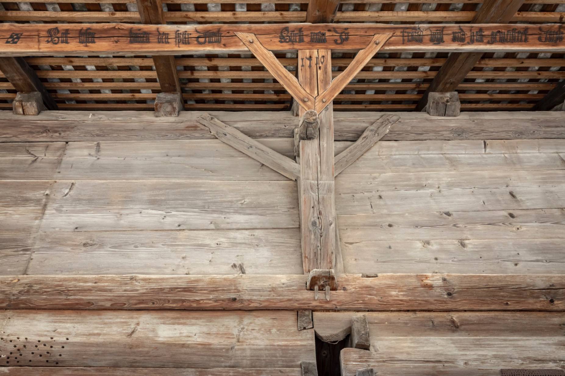 Fassade Ost. Flugpfette mit Inschrift, Mittelständer und Rähmbalken sowie Schwalbenschwanzverkämmung der beiden Blockkammern. Foto Elia Schneider, 2023